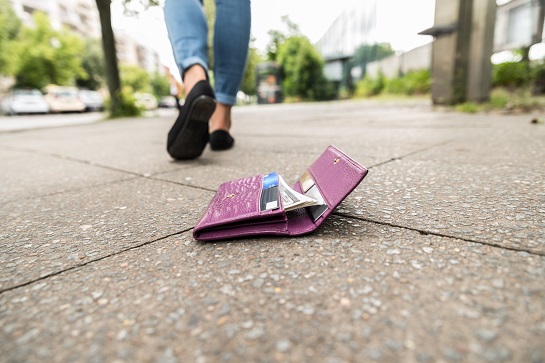 Lady walking away from her wallet on the ground  Featured Image